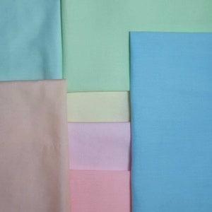 May include: A collection of fabric swatches in various pastel colors, including light blue, pale green, peach, yellow, pink, and a deeper pink.
