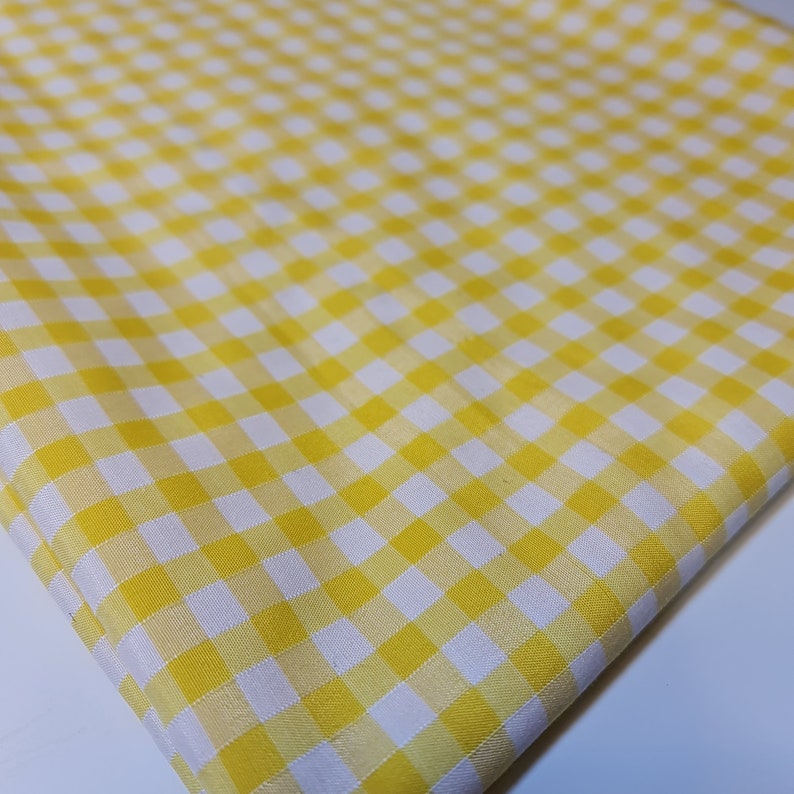 May include: Yellow and white gingham fabric with a checkered pattern.