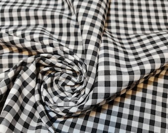 May include: Black and white gingham fabric with a small check pattern. The fabric is folded and twisted, creating a swirl effect.