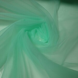May include: A piece of soft, mint green tulle fabric. The fabric is sheer and delicate, with a slightly crinkled texture.