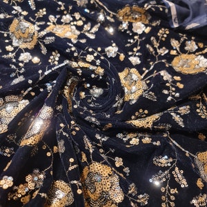 K&ouml;nnte beinhalten: Schwarzer Samtstoff mit goldenen und silbernen Pailletten in einem Blumenmuster.
