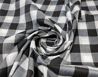 May include: Black and white gingham fabric with a large check pattern. The fabric is folded and draped, showing the texture and weave.