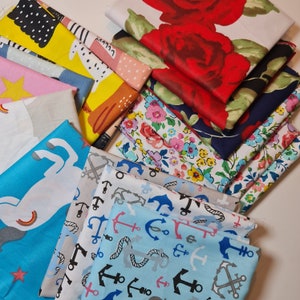 Könnte beinhalten: Eine Sammlung von Stoffresten in verschiedenen Mustern und Farben, darunter florale, nautische und abstrakte Designs. Die Stoffe sind in einem Stapel angeordnet, wobei sich einige überlappen.