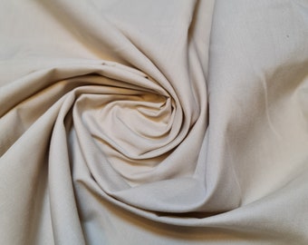 May include: A close-up of a beige fabric with a soft, smooth texture. The fabric is folded and draped, creating a smooth, flowing look.