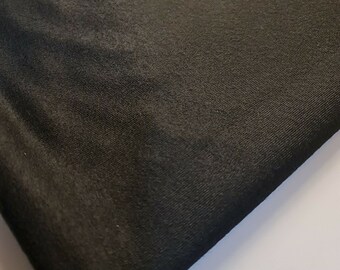 May include: Black fabric with a smooth, slightly shiny texture. The fabric is folded over on itself, showing the underside.
