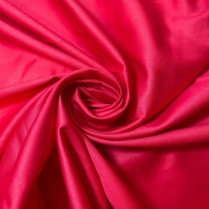 May include: Close-up of a vibrant red fabric with soft, flowing folds. The fabric is smooth and silky, creating a luxurious and elegant look.