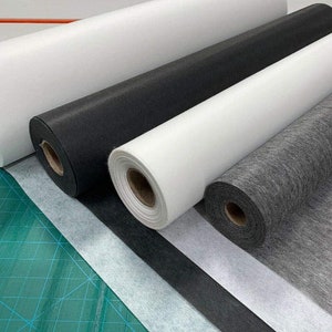 May include: Four rolls of fusible interfacing fabric in white, black, and gray. The rolls are stacked on top of each other.