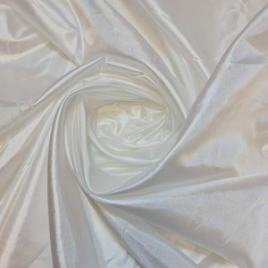 May include: White satin fabric with a smooth, silky texture. The fabric is draped and folded, creating a soft, flowing look.