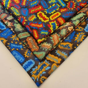 May include: Three pieces of fabric with a black background and colorful comic book style words like "BOOM!" and "KAPOW!" printed on them.