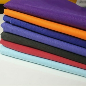 Puede incluir: Un conjunto de seis muestras de tela en diferentes colores, incluyendo morado, naranja, azul, negro, rojo y azul claro.