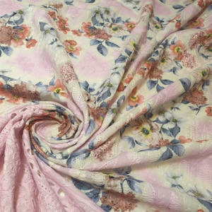 Könnte beinhalten: Rosa-weißer Blumenstoff mit zartem Spitzenmuster. Der Stoff ist weich und leicht und eignet sich daher perfekt für eine Vielzahl von Nähprojekten.