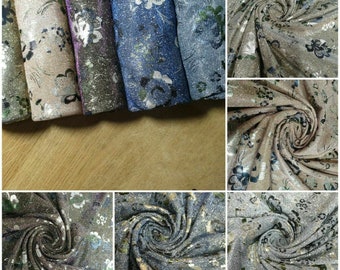 May include: A collection of eight fabric swatches with a floral pattern. The fabrics are in various shades of blue, brown, and beige. The fabrics have a shimmery, glittery texture.