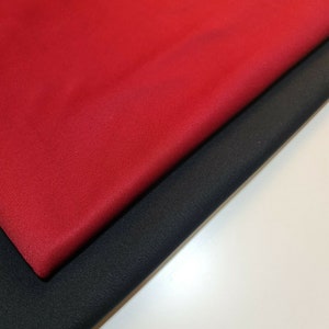 May include: Two fabric swatches, one red and one black, are folded over each other. The red fabric is on top and the black fabric is underneath.