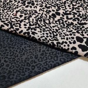 Op de afbeelding: Twee stukken stof met een luipaardprint. De ene stof is zwart met een reliëf van fluweel en de andere is een doorschijnende beige stof met zwarte vlekken.