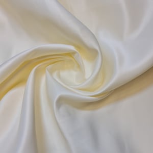 May include: Creamy white satin fabric with a soft, flowing drape. The fabric is smooth and luxurious, with a subtle sheen.