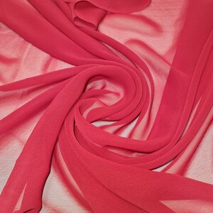 Puede incluir: Primer plano de una tela transparente de color rojo brillante, mostrando su textura y caída. La tela es suave y fluida, con una calidad delicada y casi translúcida.