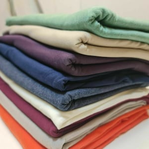 May include: A stack of folded fabric in various colors, including green, beige, purple, blue, gray, burgundy, and orange.
