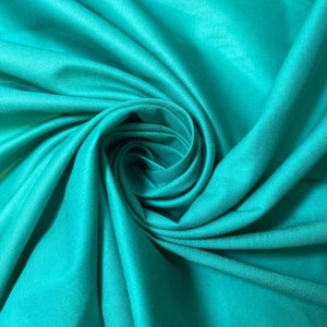 May include: A close-up of a teal fabric draped and folded in a swirling pattern. The fabric is smooth and has a soft, silky texture.
