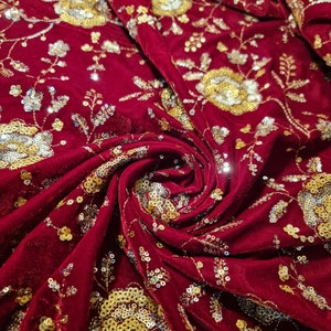 K&ouml;nnte beinhalten: Roter Samtstoff mit goldenen und silbernen Pailletten, die in einem Blumenmuster gestickt sind.