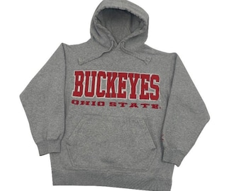 May include: A grey hooded sweatshirt featuring the word "BUCKEYES" in red lettering across the chest, with "OHIO STATE" in red below. The sweatshirt has a front pocket and a drawstring hood.