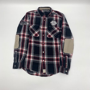 Può includere: Camicia di flanella a quadri neri, rossi e bianchi con toppe sui gomiti color beige. Presenta chiusura con bottoni, due tasche sul petto e toppe con il testo "H-D" e "H-D/MC". Una camicia casual a maniche lunghe.