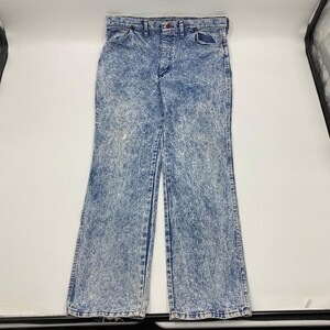 May include: Acid wash denim jeans with a classic five-pocket design. The jeans have a button and zipper closure, belt loops, and a faded blue and white pattern. The jeans are a vintage style.