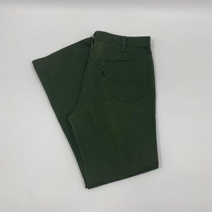 Op de afbeelding: Donkergroene broek met een klassiek vijf-zakken ontwerp. De broek heeft een rechte pijp en een knoop- en ritssluiting. De stof lijkt een duurzame katoenmix te zijn. De broek ligt plat op een wit oppervlak.