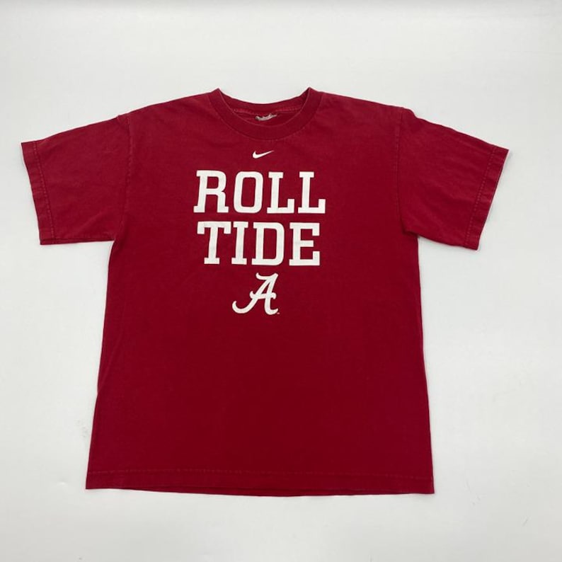 Puede incluir: Camiseta roja carmes&iacute; con el texto blanco "ROLL TIDE A". Un peque&ntilde;o logotipo de Nike est&aacute; encima del texto. La camiseta de manga corta est&aacute; hecha de un material suave. Un dise&ntilde;o cl&aacute;sico.