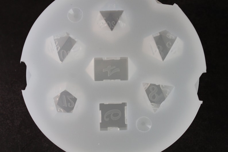 Puede incluir: Molde de silicona blanco con siete formas diferentes para hacer dados. El molde tiene una forma circular y est&aacute; dise&ntilde;ado para crear un d4, d6, d8, d10, d12 y d20.