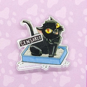 May include: A black cat with yellow eyes sits in a blue litter box. The cat is censored with a white rectangle that says "CENSORED". The image is on a pink background with white paw prints.