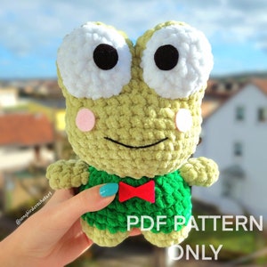 May include: Crochet amigurumi frog pattern. The frog is green with a red bow tie and big white eyes. The pattern is available as a PDF download.  PDF PATTERN ONLY.