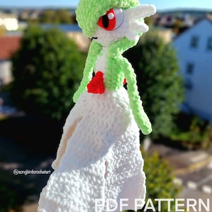 Peut inclure: Poupée Gardevoir au crochet faite à la main. La poupée a une tête et des bras verts, un corps blanc et des détails rouges. Le texte "PDF PATTERN ONLY" est visible. Personnage de la franchise Pokémon.