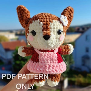 Peut inclure: Patron de crochet pour un animal amigurumi brun et blanc portant une robe rose et rouge avec une fleur blanche sur la tête. Le patron est disponible en téléchargement PDF.  PDF PATTERN ONLY.
