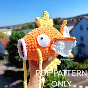 Peut inclure: Poisson orange crocheté avec des détails jaunes et blancs. Le texte "PDF PATTERN ONLY" est affiché en bas. Le poisson a un œil blanc et une bouche rose. Article fait main.