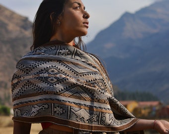 Chal peruano de alpaca: tejido a mano con animales sagrados, tonos tierra y estilo ceremonial andino.