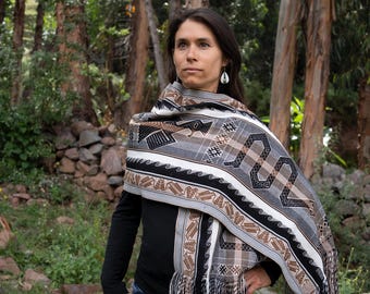 Chal peruano de alpaca: tejido a mano con animales sagrados, tonos tierra y estilo ceremonial andino.