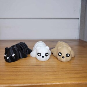 K&ouml;nnte beinhalten: Drei kleine, im 3D-Druck hergestellte Cartoon-B&auml;ren. Die B&auml;ren liegen und haben gro&szlig;e Augen. Die B&auml;ren sind schwarz, wei&szlig; und braun.