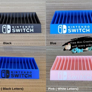 May include: A collection of Nintendo Switch game organizers in black, blue, and pink. Each organizer features vertical slots for game cartridges and the Nintendo Switch logo. The image also includes the text "Free Mini Creature with every order!"