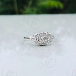 May include: A silver ring with a unique design featuring a cluster of small stones set in a leaf-shaped pattern.