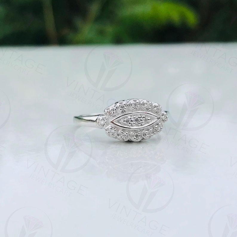 May include: A silver ring with a unique design featuring a cluster of small stones set in a leaf-shaped pattern.