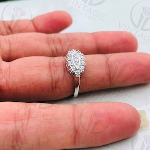 May include: A silver ring with a clear oval-shaped stone surrounded by smaller clear stones.