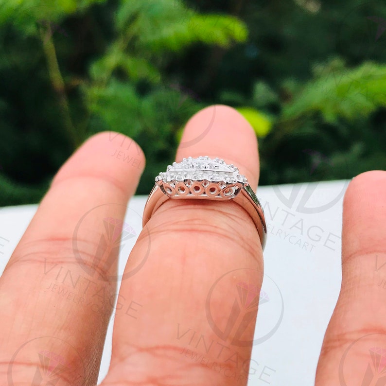 May include: A silver ring with a row of small, clear stones set in a leaf-shaped design.