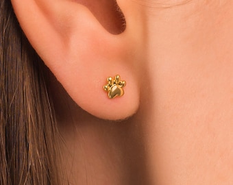 May include: A pair of gold paw print stud earrings. The earrings are small and delicate, and they would make a great gift for any dog lover.