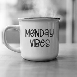 Pu&ograve; includere: Tazza in ceramica bianca con bordo nero e il testo "Monday Vibes" in un carattere nero stilizzato.
