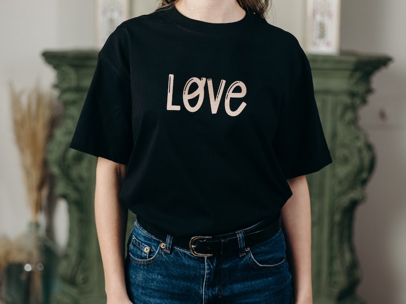 Pu&ograve; includere: Una maglietta nera con la parola "Love" scritta in color marrone chiaro sul davanti.