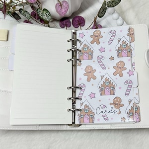May include: White planner with a gingerbread house and candy cane pattern on the dividers. The dividers are labeled "Cards".