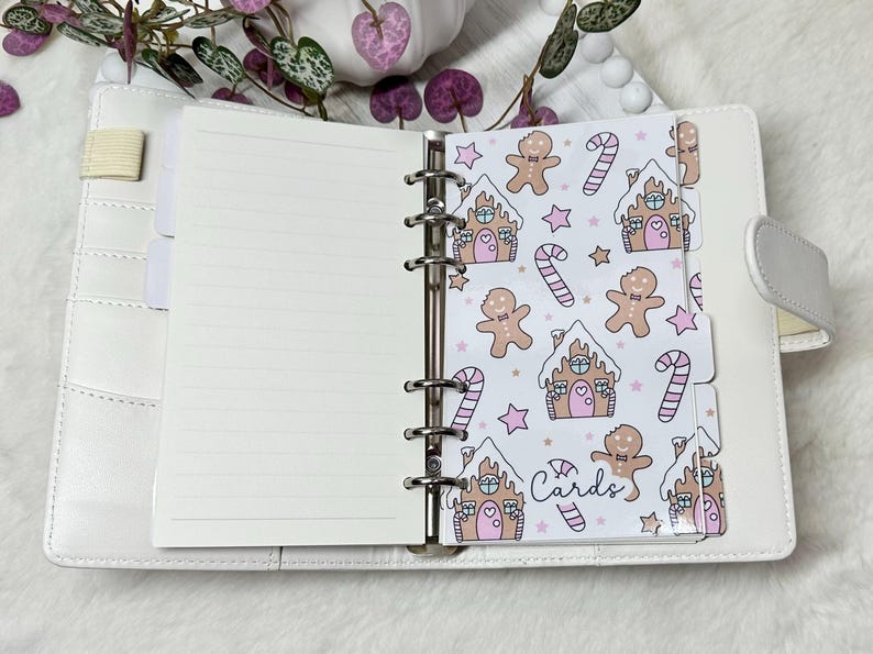 May include: White planner with a gingerbread house and candy cane pattern on the dividers. The dividers are labeled "Cards".