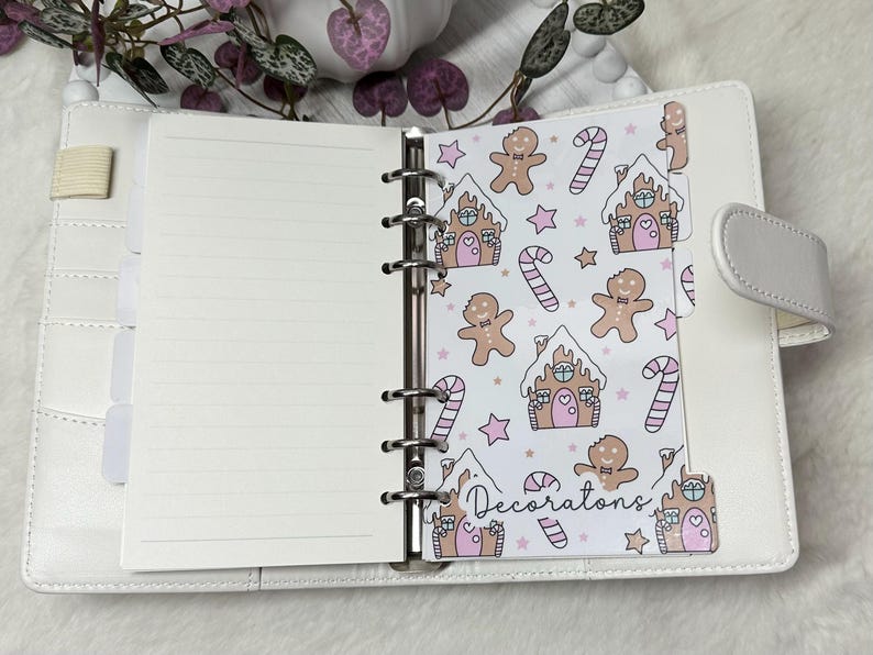 May include: A white planner with a gingerbread house and candy cane pattern on the tab. The tab says "Decorations".