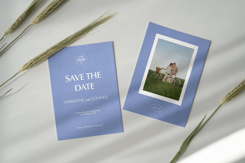 May include: A blue save the date card with white text that reads "Save the Date" and "Marianne and Connell". The card also includes the date "June 14, 2025" and the text "Ceremony and Celebration in Camocilla, ME". A second card features a photo of a couple riding a bicycle in a field.