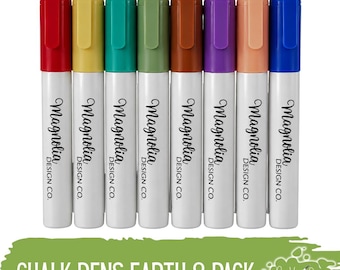 May include: A set of eight chalk pens in red, yellow, teal, olive green, brown, purple, peach, and blue. Each white barrel features the text Magnolia Design Co. The bottom green graphic includes the text CHALK PENS EARTH 8 PACK.